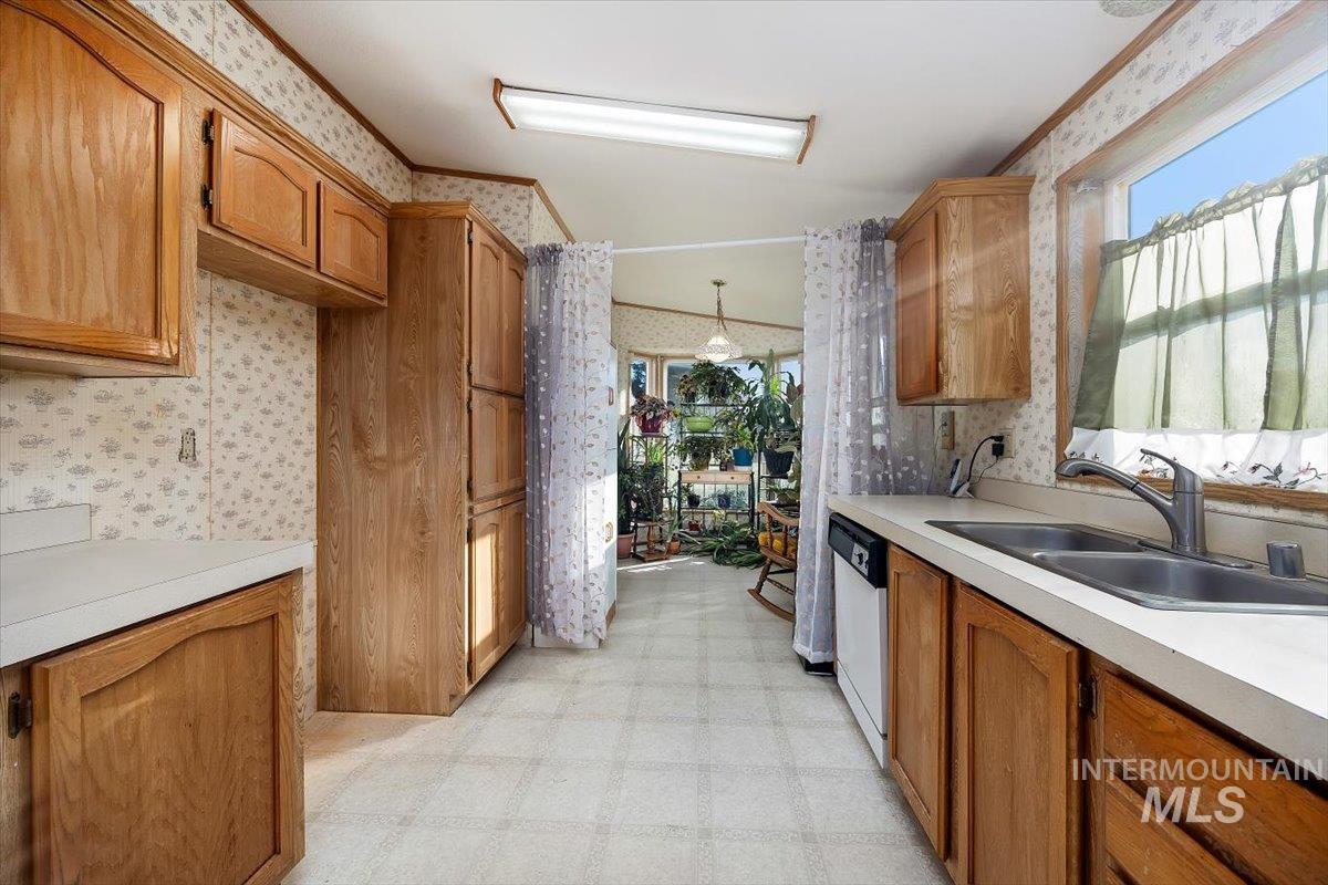198 South Hills Road, Unit 142 Twin Falls, ID 83301 - Photo 14 of 27 Kitchen with light floors, brown cabinets, light countertops, wallpapered walls, and decorative light fixtures