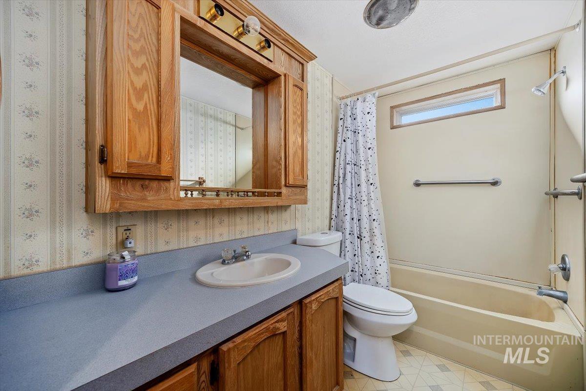198 South Hills Road, Unit 142 Twin Falls, ID 83301 - Photo 24 of 27 Full bathroom with vanity, shower / bath combo with shower curtain, and wallpapered walls