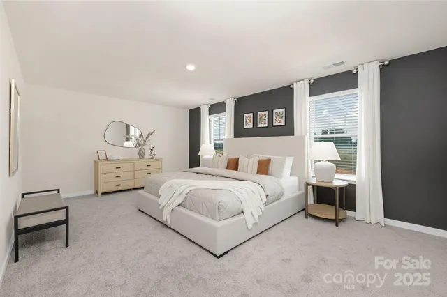 a spacious bedroom with a bed a table and painting