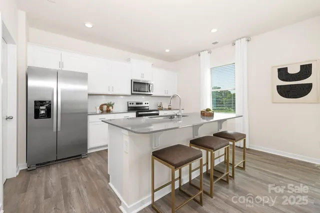 a kitchen with kitchen island granite countertop a sink cabinets and stainless steel appliances