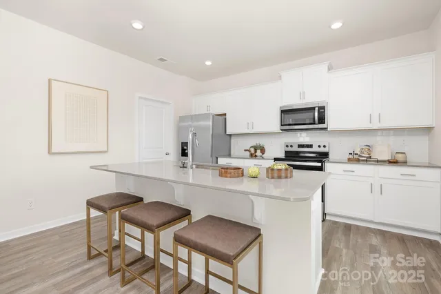 a kitchen with stainless steel appliances a stove a sink a microwave a refrigerator and cabinets