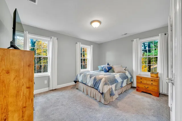 a bed sitting in a spacious bedroom next to a window