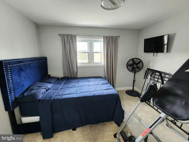 a bedroom with a bed and a flat tv screen on the dresser