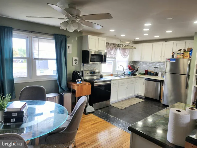 a kitchen with stainless steel appliances granite countertop a sink a stove a refrigerator cabinets and a dining table