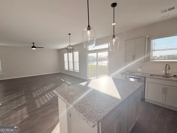 a kitchen with stainless steel appliances granite countertop a sink a oven a dining table and chairs with wooden floor