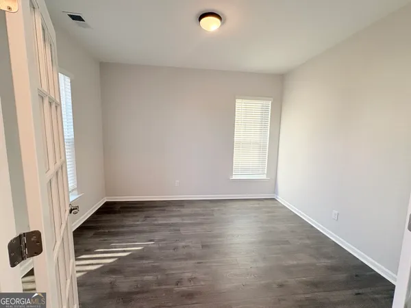 an empty room with wooden floor and windows