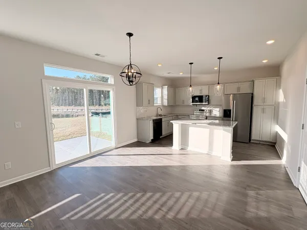 a view of large kitchen with stainless steel appliances kitchen island a stove a refrigerator a sink dishwasher with a dining table and chairs