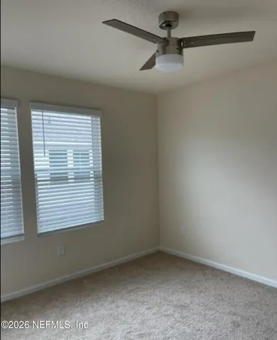 an empty room with a window and a fan