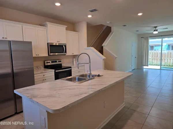 a kitchen with kitchen island granite countertop a sink refrigerator and microwave
