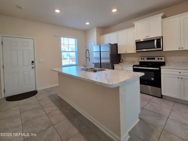 a kitchen with stainless steel appliances a sink a stove a microwave a counter top space and cabinets