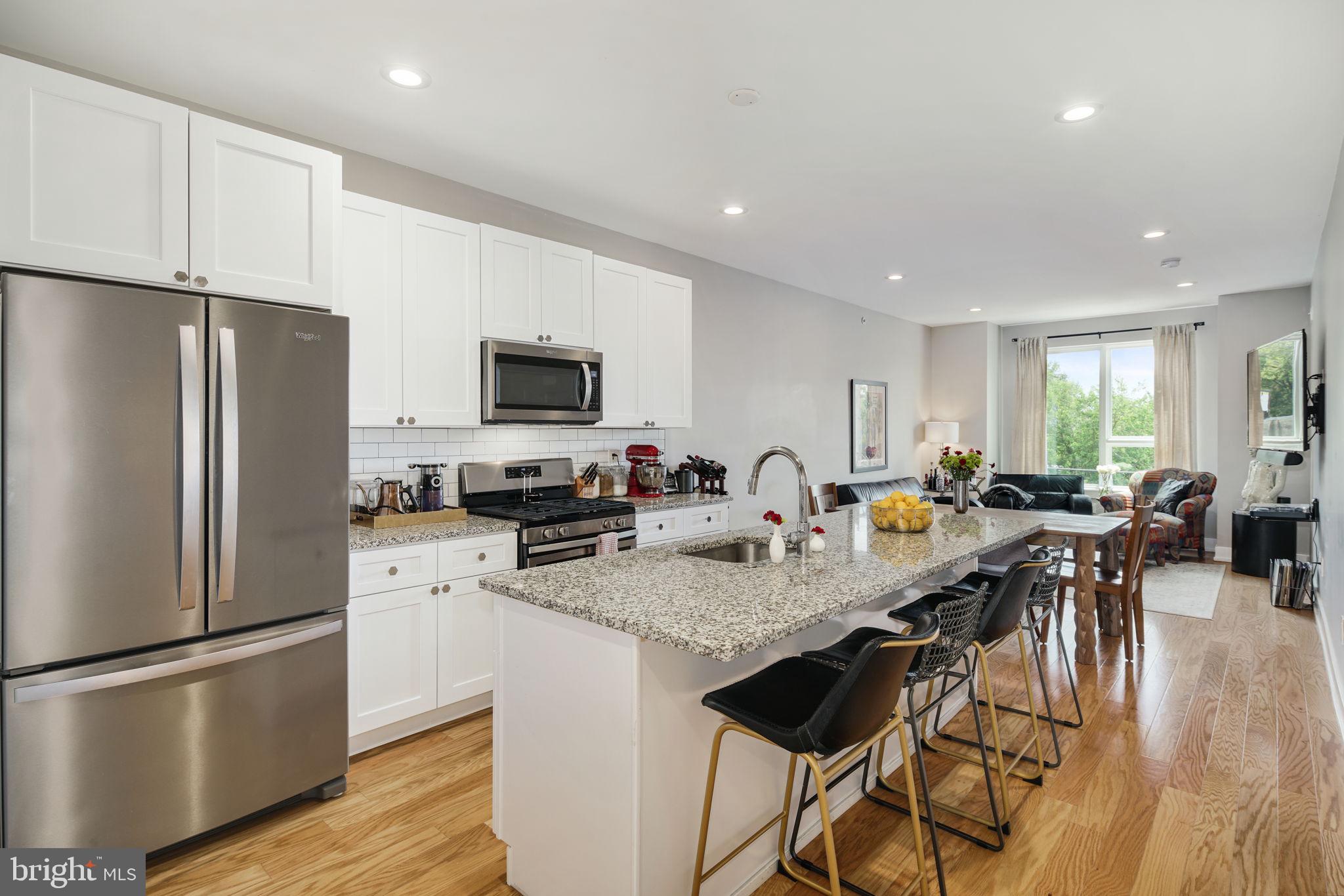 2711 West Jefferson Street, Unit 2 Philadelphia, PA 19121 - Photo 1 of 27 a kitchen with stainless steel appliances granite countertop a refrigerator a stove a sink a microwave a dining table and chairs with wooden floor