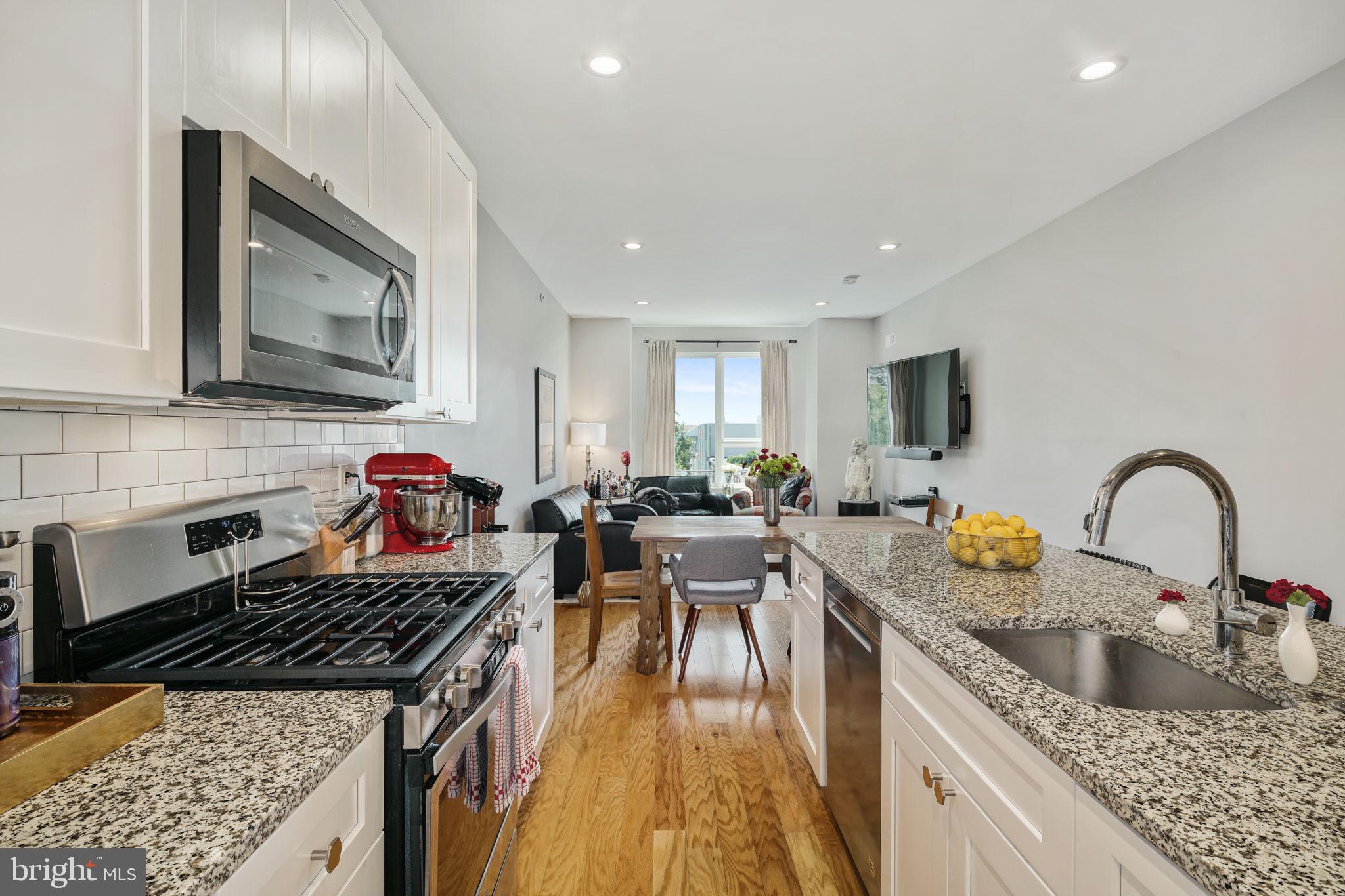 2711 West Jefferson Street, Unit 2 Philadelphia, PA 19121 - Photo 2 of 27 a kitchen with a stove a sink a kitchen island with a dining table and chairs