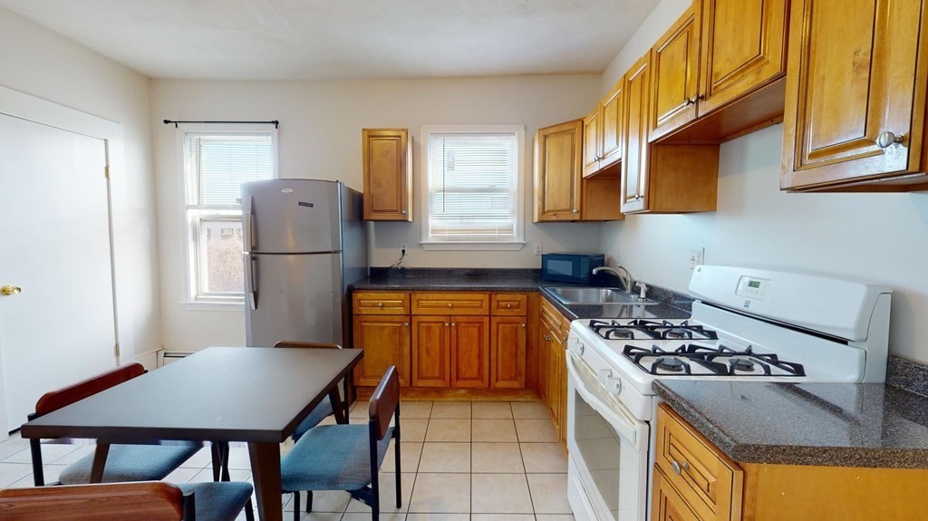 11 Elder Street, Unit 3 Boston, MA 02125 - Photo 1 of 26 a kitchen with a stove a refrigerator and a dining table