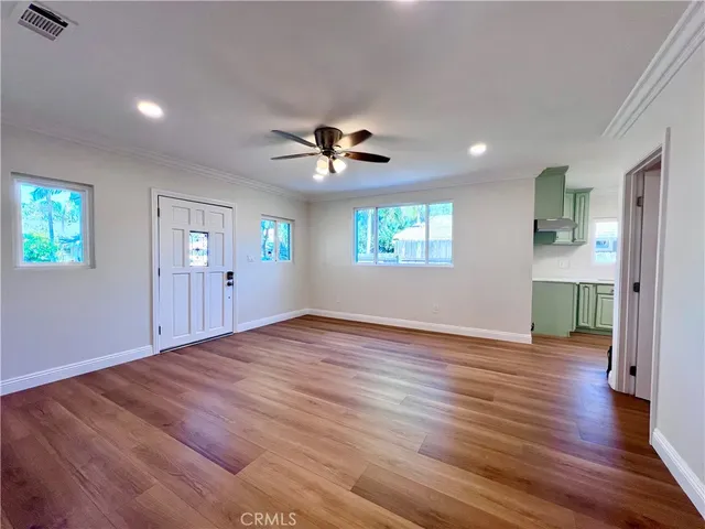 a view of an empty room with window and wooden floor