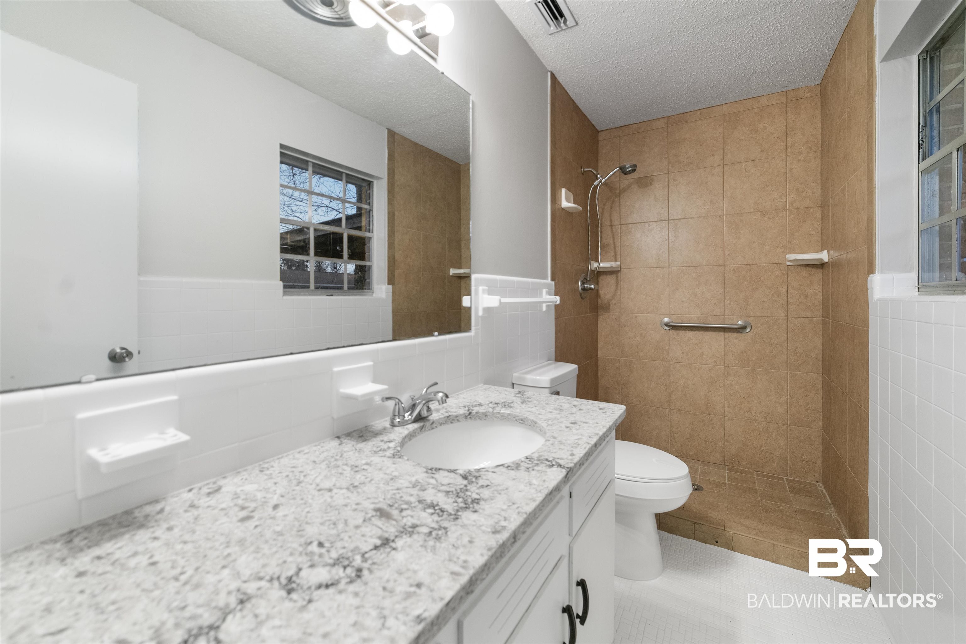 11833 Old Moffat Road Wilmer, AL 36587 - Photo 14 of 23 Bathroom with tile walls, visible vents, toilet, vanity, and a textured ceiling