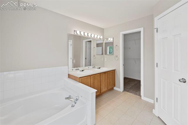 6725 Akron Road Colorado Springs, CO 80923 - Photo 23 of 50 Bathroom featuring tile patterned floors, a washtub, and dual bowl vanity