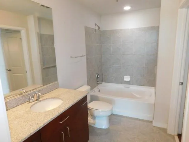 a bathroom with a granite countertop sink a toilet and bathtub