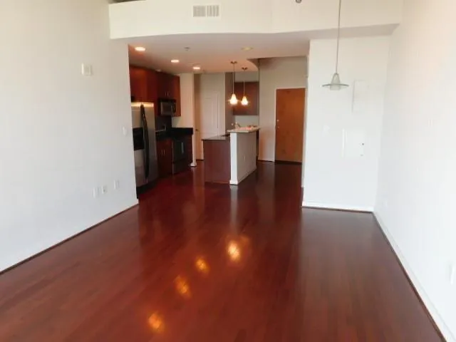 a view of a hallway with wooden floor and a kitchen