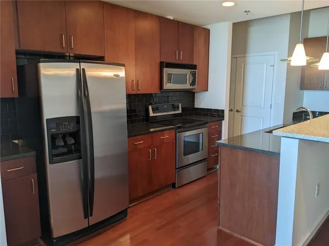 a kitchen with stainless steel appliances granite countertop a refrigerator stove and sink