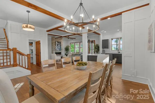 a dining room with wooden floor a chandelier a wooden table and chairs