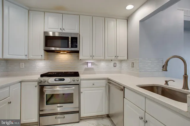 a kitchen with white cabinets stainless steel appliances and sink