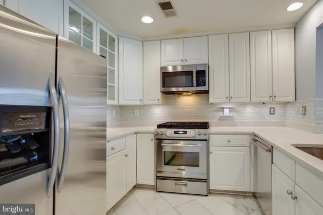 a kitchen with white cabinets and stainless steel appliances