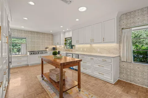 a kitchen with kitchen island a stove a sink a refrigerator and blue cabinets with wooden floor