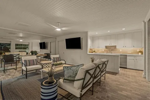 a living room with furniture a flat screen tv and kitchen view