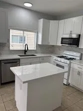 a kitchen with granite countertop a sink a stove and a microwave