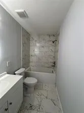a bathroom with a granite countertop sink a toilet and shower
