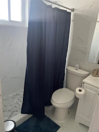 a white toilet sitting next to a shower curtain