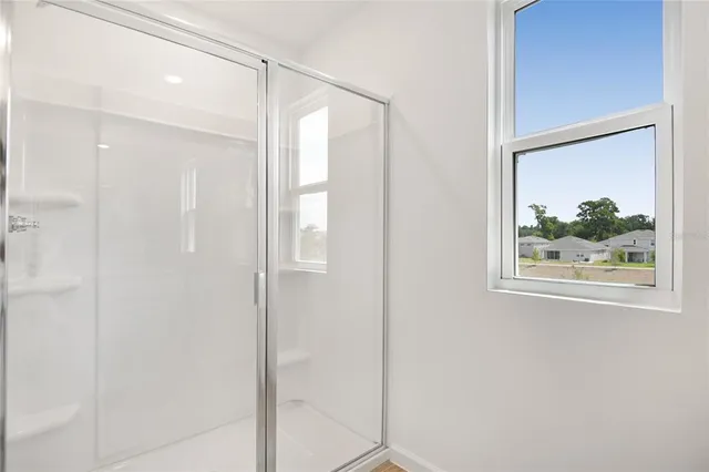 a bathroom with a glass shower door and a window