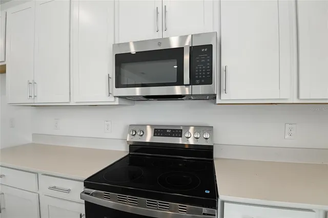 a kitchen with stainless steel appliances granite countertop white cabinets and a stove top oven