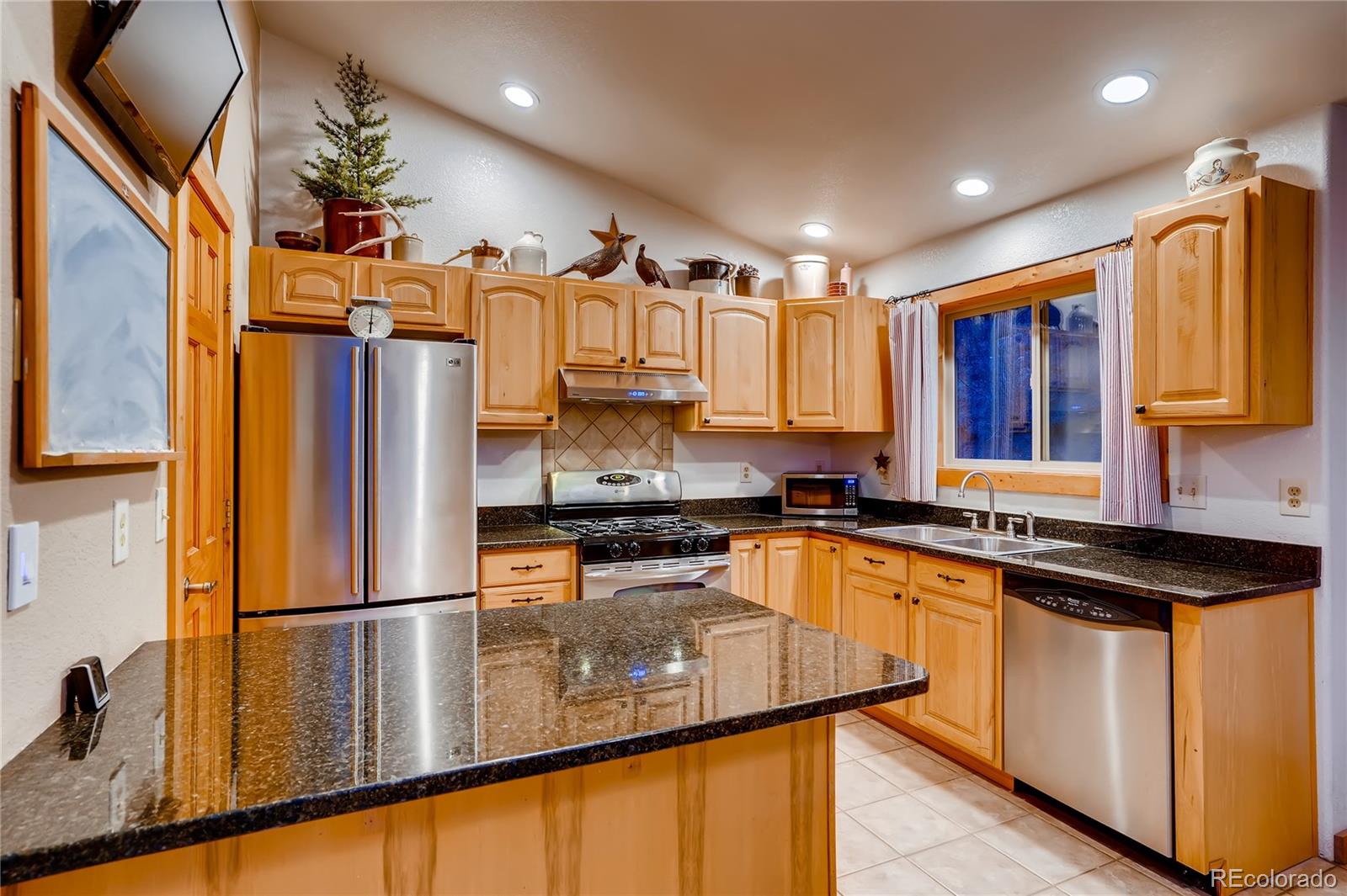 7120 County Road 43 Bailey, CO 80421 - Photo 19 of 37 a kitchen with stainless steel appliances granite countertop a refrigerator a sink dishwasher a stove and a dining table with wooden floor