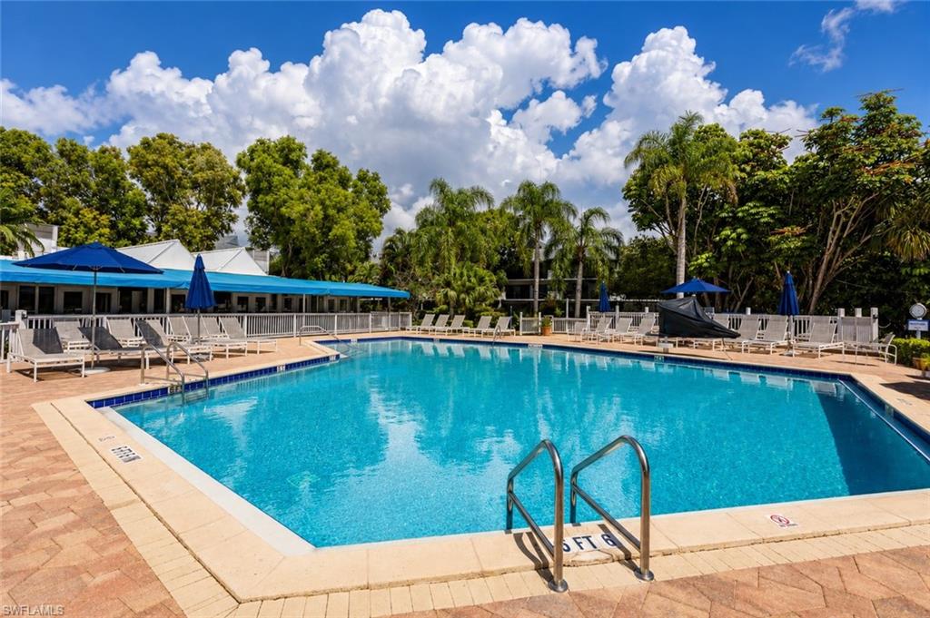 600 Neapolitan Way, Unit 449 Naples, FL 34103 - Photo 22 of 44 Community swimming pool featuring a brick paver deck and lounge seating