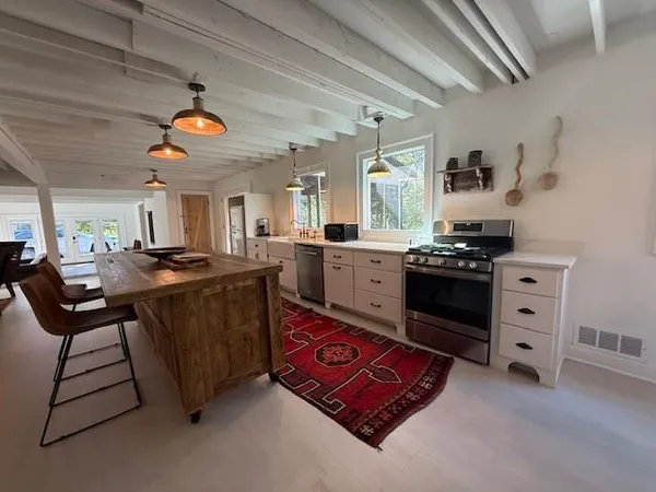 a kitchen with stainless steel appliances granite countertop a stove a sink dishwasher and a dining table with the kitchen view