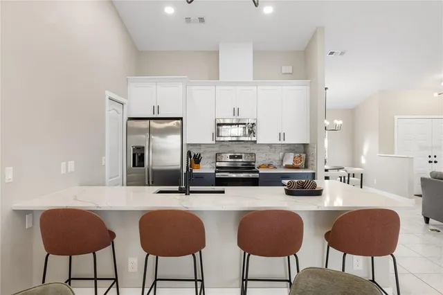 a kitchen with stainless steel appliances a dining table chairs microwave and sink
