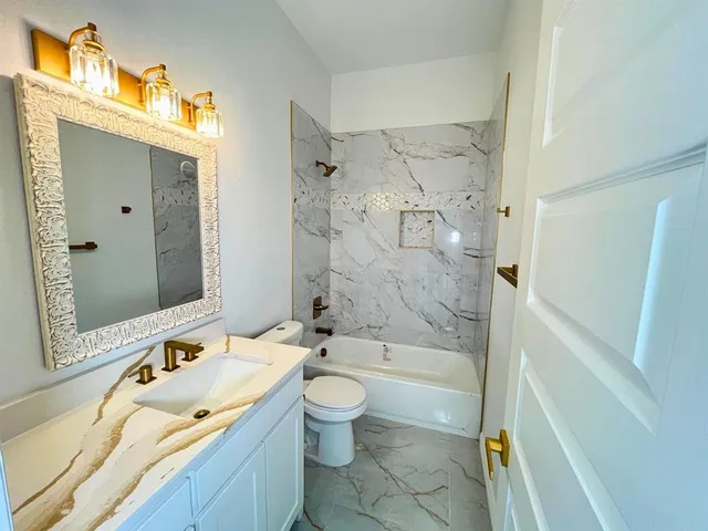a bathroom with a granite countertop sink toilet and shower
