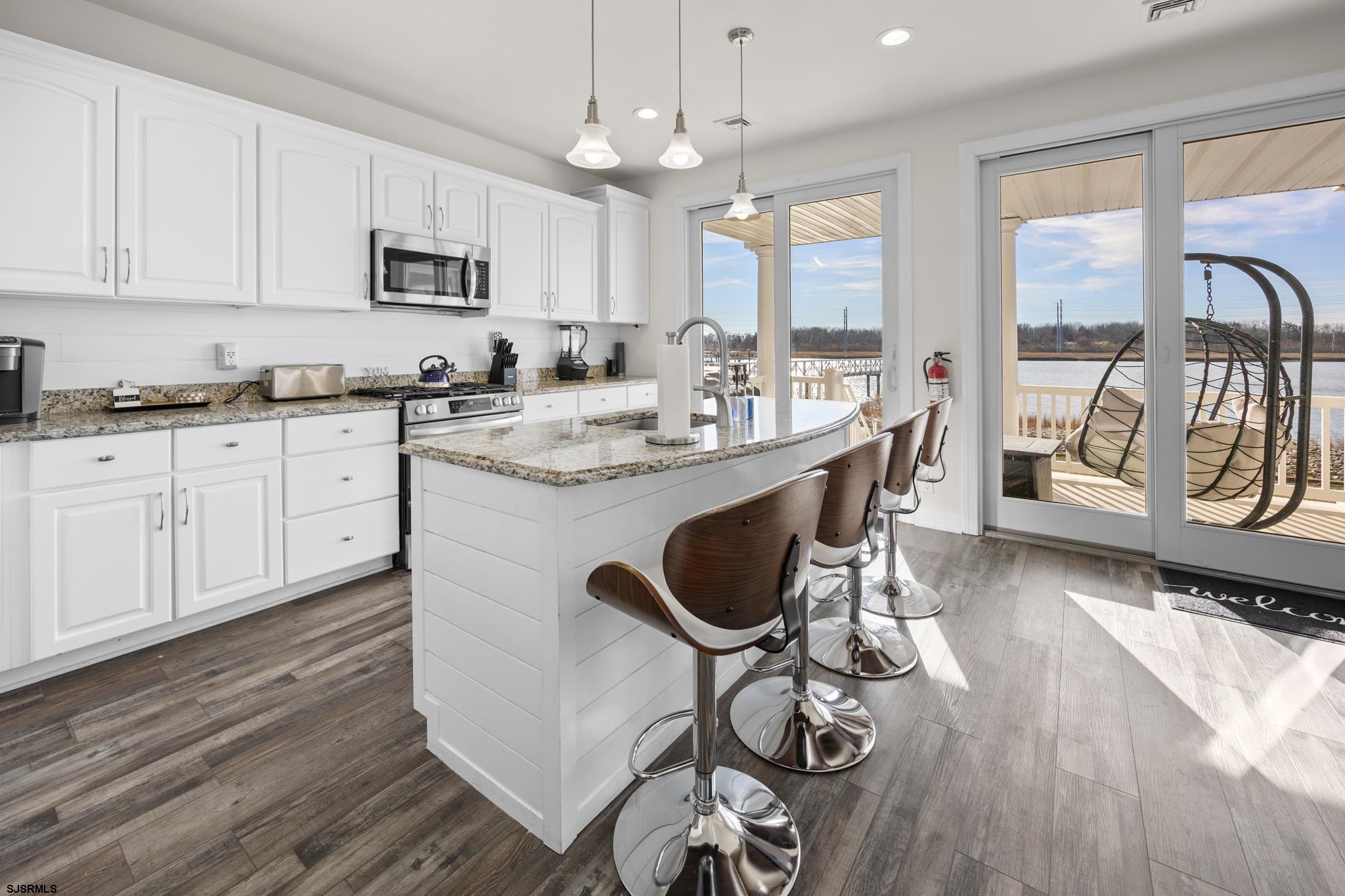 2010 West Riverside Drive Atlantic City, NJ 08401 - Photo 9 of 58 a kitchen with stainless steel appliances granite countertop a stove top oven a sink a dining table and chairs with wooden floor