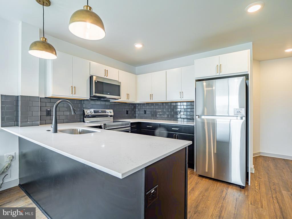 a kitchen with stainless steel appliances a refrigerator a stove a sink a center island and a cabinets