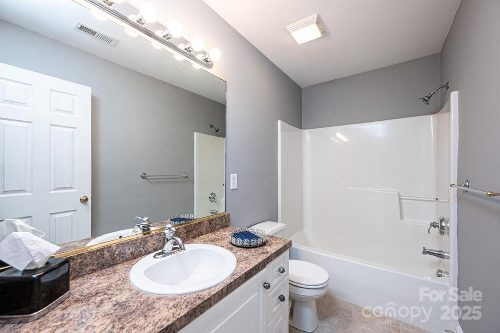 2594 Knoll Ridge Court Hickory, NC 28602 - Photo 25 of 43 a bathroom with a granite countertop sink a toilet a mirror and shower