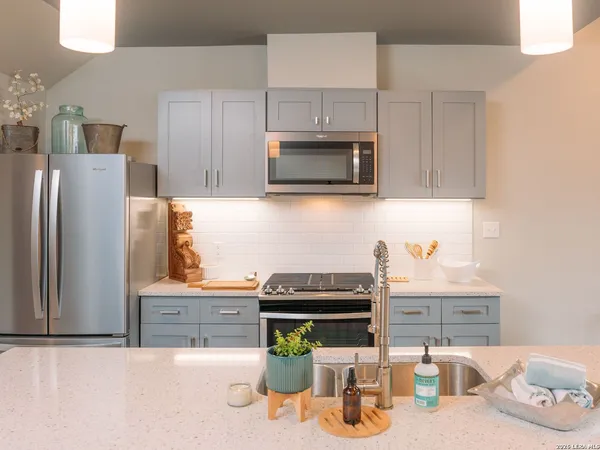 a kitchen with granite countertop a refrigerator and a stove top oven
