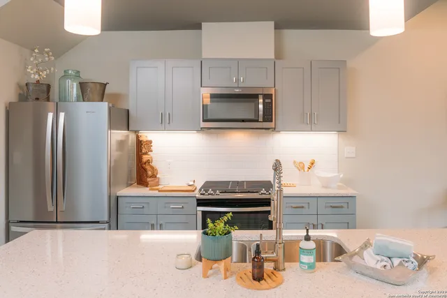 a kitchen with granite countertop a refrigerator and a stove top oven