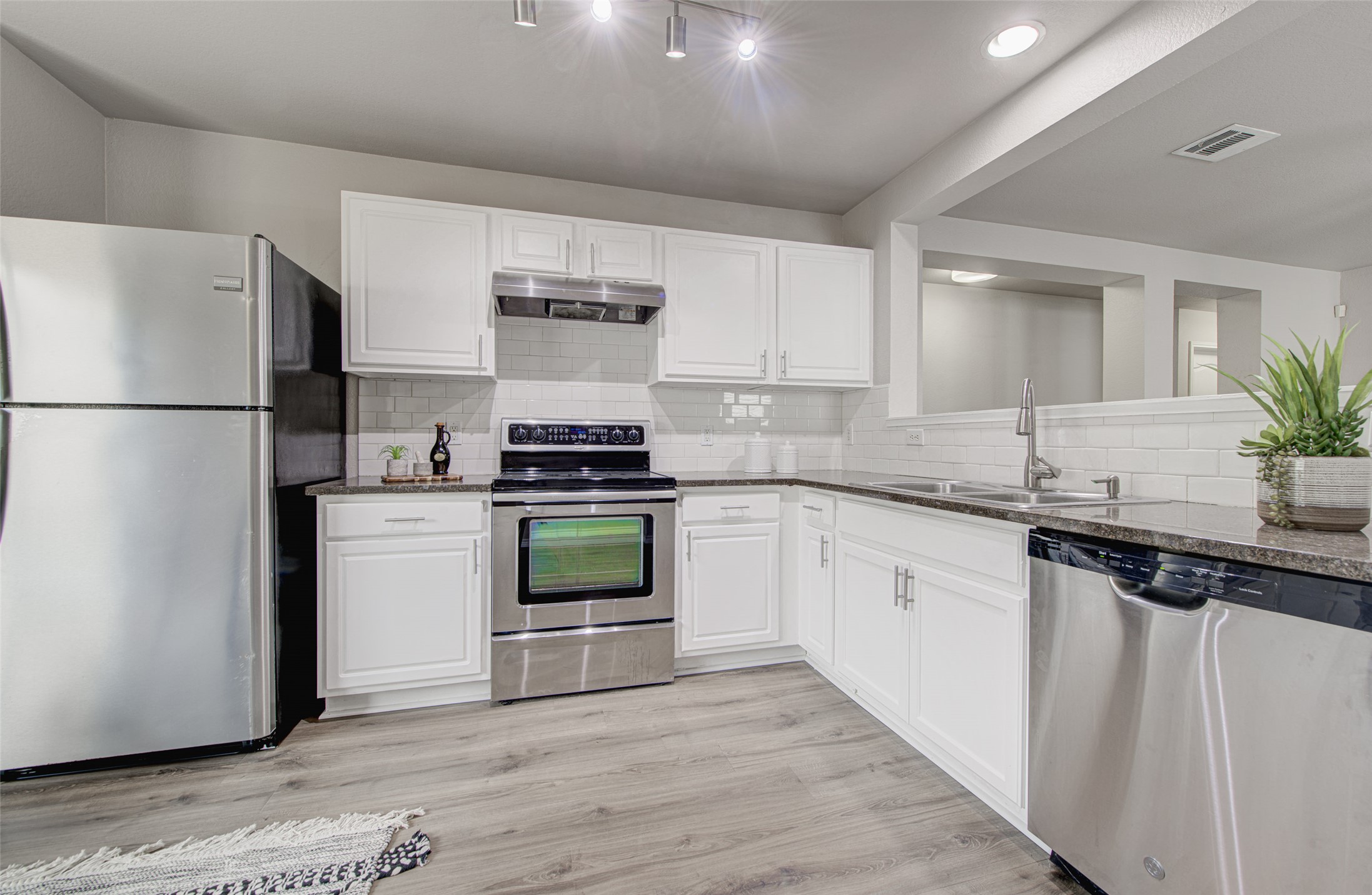 6709 Doyal Drive Austin, TX 78747 - Photo 9 of 22 Kitchen featuring stainless steel appliances, light wood-type flooring, and white cabinetry