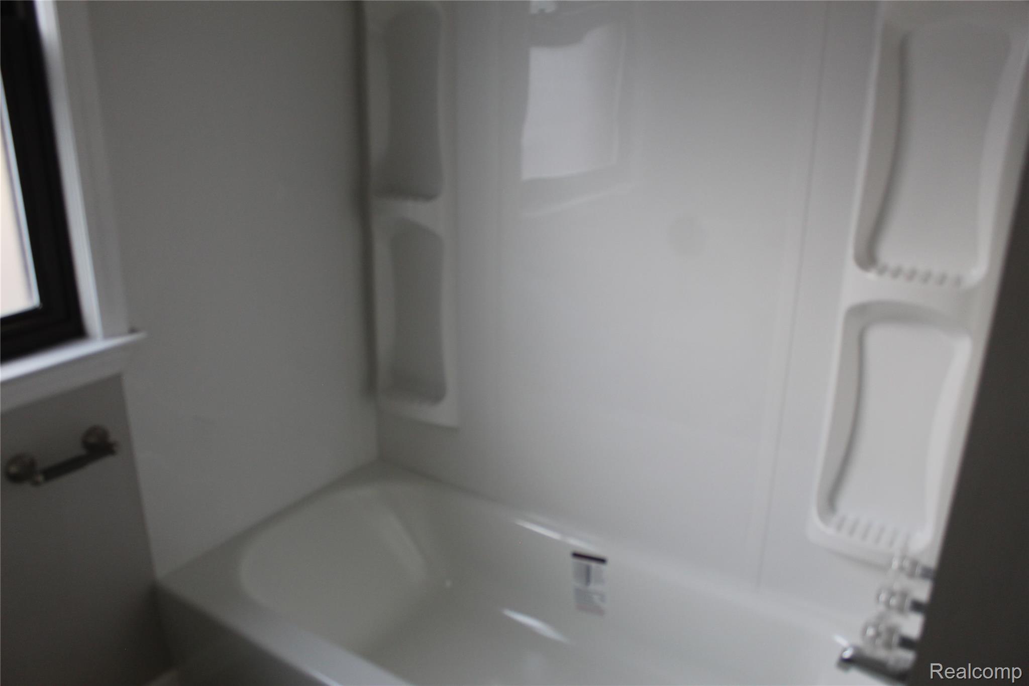 5543 Balfour Road Detroit, MI 48224 - Photo 39 of 54 White bathtub with integrated shower surround featuring recessed shelving