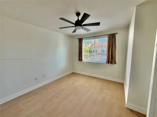 an empty room with a window and a ceiling fan