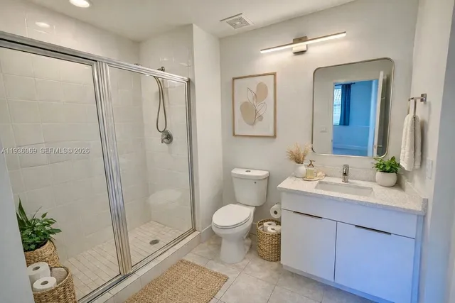 a bathroom with a shower sink vanity mirror and toilet