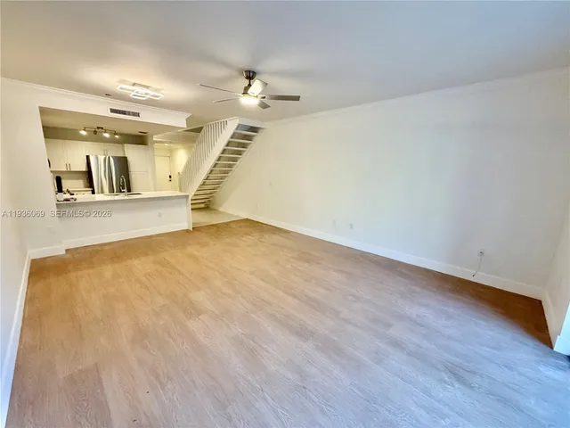 an empty room with wooden floor chandelier fan and windows