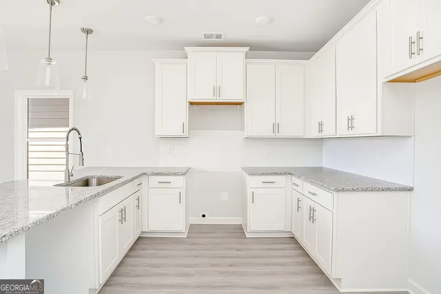 a large white kitchen with granite countertop a stove a sink and dishwasher with white cabinets