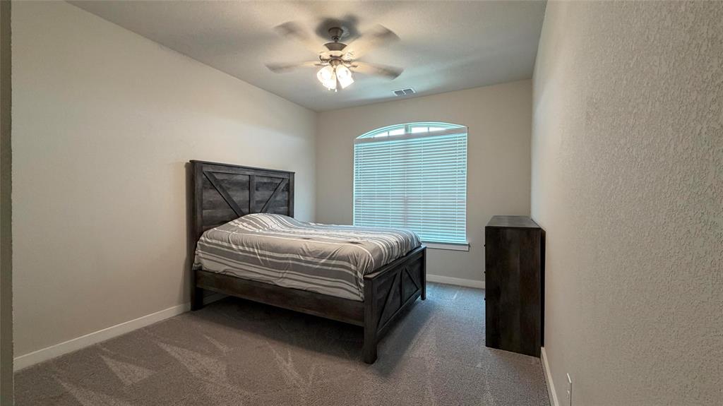 912 Fallbrook Avenue Denton, TX 76210 - Photo 18 of 26 a bed sitting in a bedroom next to a window and a chandelier